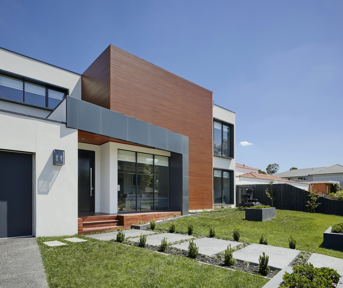 Modern Christchurch-style home with dark stained timber boundary fence and deck steps