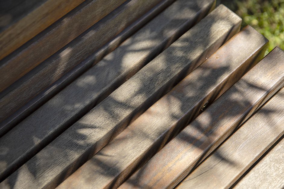 Close-up of weathered hardwood deck boards dappled with leaf shadows