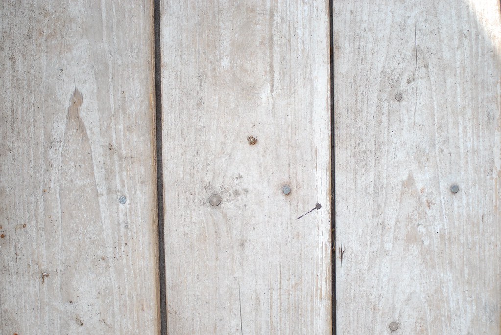Close-up of silvered weathered painted fence boards with nail fixings